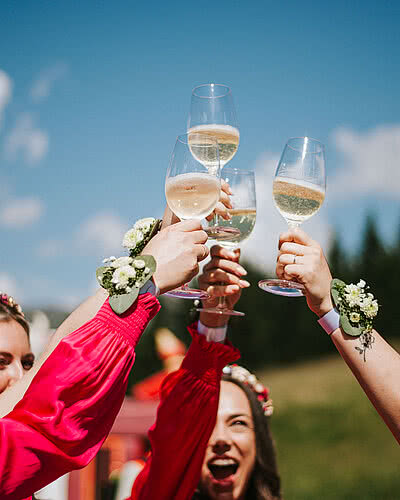 Anstoßen auf die Liebe – Sommerhochzeit am Vermala Wirt Frauen stoßen mit Sektgläsern bei sonniger Sommerhochzeit am Vermala Wirt im Montafon an