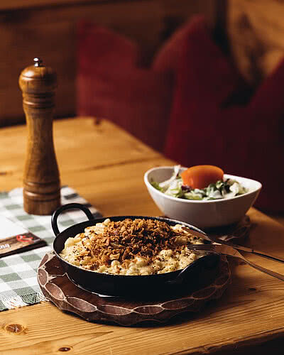Käsespätzle mit Röstzwiebeln und Salat | Vermala Wirt – Berghütte im Montafon Frisch zubereitete Montafoner Käsespätzle mit Röstzwiebeln beim Vermala Wirt – perfekter Genussmoment beim Skifahren oder Wandern im Silvretta Montafon.